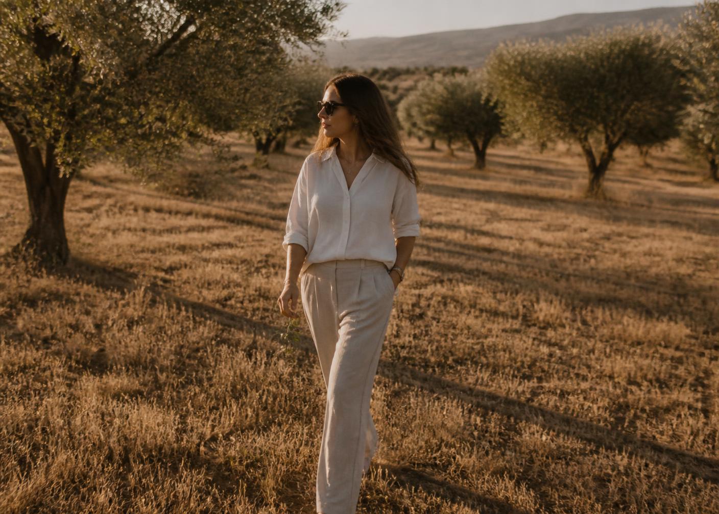 Woman walking among olive trees in golden afternoon light